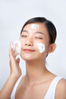 © Marc Tran/Stocksy - Beautiful asian woman applying cleansing foam on facial skin