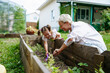 © AD Astra Team/Stocksy - Mom and daughter plant seeds in the garden