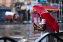 Photographer Taking Shots With Mobile In Street Holding An Umbrella 