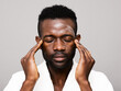 © ohlamour studio/Stocksy - Relaxed man massaging his face with beauty product