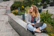 © Strelciuc - Young pretty woman wearing eyeglasses sitting with laptop outdoors, online learning concept. Copy space. Millennial people spend time outside. Working remotely