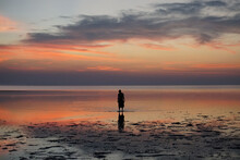 A Man Standing In The Colorful Water During Sunset In Thailand
