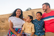 © ByLorena/Stocksy - Multiracial happy family sitting at field portrait