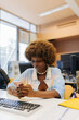 © VICTOR TORRES/Stocksy - Cheerful afro woman using smartphone in classroom