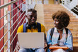 © VICTOR TORRES/Stocksy - Couple sitting on stairs at university and working on laptop