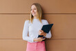 © VICTOR TORRES/Stocksy - Pretty young girl holding folder over brown wall