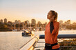 © Drazen - Athletic woman with eyes closed enjoys in music on quay at sunset.