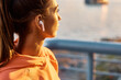 © Drazen - Close up of female athlete listening music over earbuds at sunset.