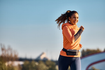 Wall Mural - Happy sportswoman running during her daily workout routine.