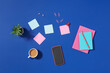 © Marc Tran/Stocksy - Top view of student table with headphone and stationery on blue