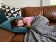 © Cara Dolan/Stocksy - Child Napping on the Couch at Home with Pillow and Blanket