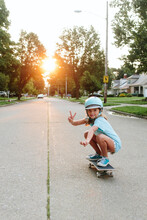 Girl Skateboards Down The Street In Early Morning Sun