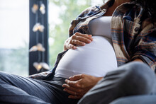 Woman Cradles Pregnant Belly While Sitting