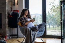 Pregnant Woman Checking Messages On Phone At Home During Holidays