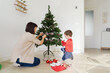 © ACALU Studio/Stocksy - Family decorating a small christmas tree at home
