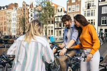 Group Of Friends Riding Bikes And Using Smartphone In Amsterdam
