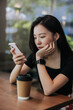 © Heng Yu/Stocksy - Woman at cafe using cellphone.