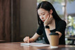 © Heng Yu/Stocksy - Young woman in a cafe reading an ebook