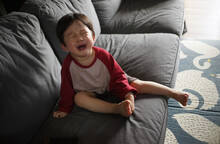 Cute Little Asian Boy Crying On The Sofa