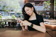 © Heng Yu/Stocksy - Woman at cafe using cellphone.