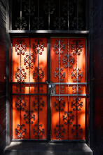 Sunlit Orange Door Behind Iron Gate