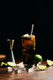 Fototapeta Uliczki - Cuba libre cocktail cold and refreshing drink for summer days on a wooden table with ice and slices of lemons
