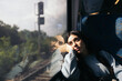 © Pedro Merino/Stocksy - Young woman traveling by train looking out the window