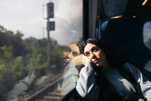 Young Woman Traveling By Train Looking Out The Window