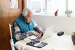 © Moy Ortega/Stocksy - Old man working from home with laptop and tablet