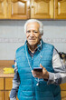 © Moy Ortega/Stocksy - Portrait of elderly man looking at camera, using mobile phone