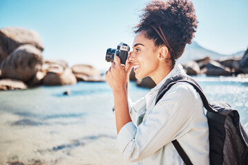 Canvas Print - Photographer, woman and camera at beach for travel vacation or holiday in summer sun. Tourist, happy photography and black woman shooting pictures on sea sand for outdoor lifestyle in sunshine