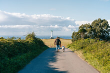 Anonymous Man With Dog Walking Towards Lighthouse