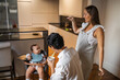 © Lupe Rodríguez/Stocksy - parents feeding their baby sitting in the highchair