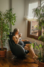 pregnant woman drinking coffee at home