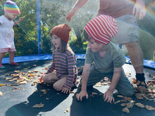 Three Children Tumbling On A Trampoline With Their Father