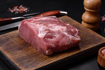 Fresh piece of raw pork with spices, salt and herbs on a wooden cutting board