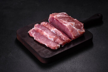 Fresh piece of raw pork with spices, salt and herbs on a wooden cutting board