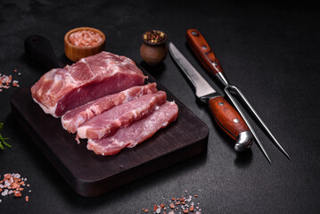 Fresh piece of raw pork with spices, salt and herbs on a wooden cutting board