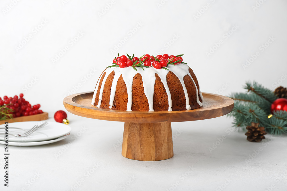 Wooden dessert stand with traditional Christmas cake on light background