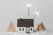 Composition with burning sparklers, Christmas decor, house model and snow on white background