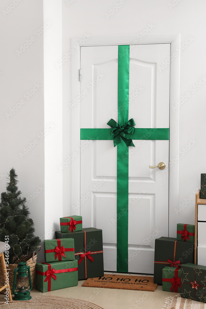 White door with green bow and Christmas presents in hall