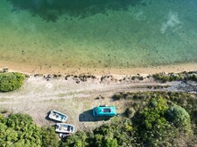 Aerial View Of A Campervan And Two Old Boats Near The Sea