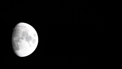 Wall Mural - Timelapse. A glowing huge moon seen from earth through the atmosphere against a starry night sky. A large moon moves across the sky, the moon moving from the left frame to the right.