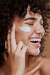 © Jade M/peopleimages.com - Happy woman, face cream and beauty, makeup product and sunscreen facial treatment for aesthetic shine. Young model, face freckles and body lotion, cosmetics and healthy skincare, wellness and melasma