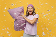 © ViDi Studio - Calm young fun woman she wears purple pyjamas jam sleep eye mask rest relax at home play pillow battle dropping feather isolated on plain yellow background studio portrait Good mood night nap concept