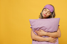 Calm Young Serene Peaceful Woman She Wears Purple Pyjamas Jam Sleep Eye Mask Rest Relax At Home Hold In Hand Pillow Close Eyes Isolated On Plain Yellow Background Studio. Good Mood Night Nap Concept.