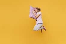 Full Body Sideways Young Woman Wear Purple Pyjamas Jam Sleep Eye Mask Rest Relax At Home Jump High Put Head On Pillow Close Eyes Isolated On Plain Yellow Background Studio Portrait. Night Nap Concept.