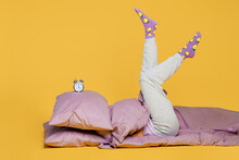 Full Body Young Woman Wears Purple Pyjamas Jam Sleep Eye Mask Rest Relax At Home Lying On Bed Duvet Cover Head With Pillow With Clock Alarm On It Isolated On Plain Yellow Background Night Nap Concept