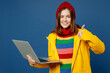 Young IT woman wear sweater red hat yellow raincoat outerwear work hold use laptop pc computer show thumb up isolated on plain dark royal navy blue background Outdoor wet fall weather season concept.