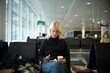 © FOLIO - Woman with coffee cup and smartphone sitting at airport